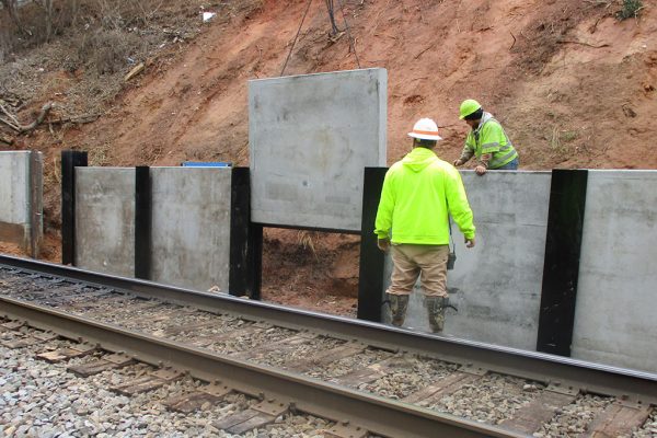 High Point Improvements - Workers place concrete panels for new retaining wall south of Wrenn Avenue
